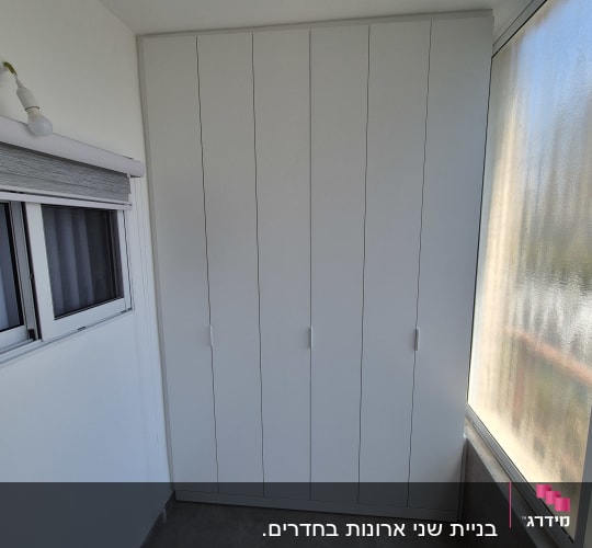 ארון לבן עם דלתות בחדר מואר